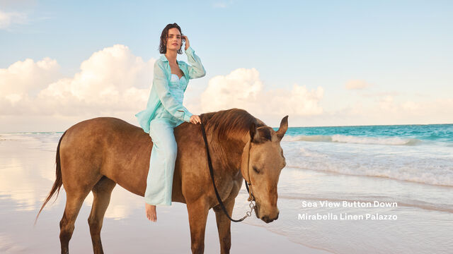Model on horseback on a beach wearing linen matching set 
